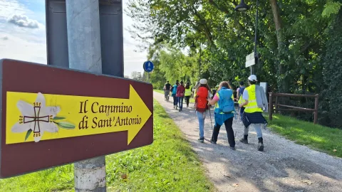 Freccia Ufficiale del Cammino di sant'Antonio posizionata lungo l'Ultimo Cammino Camposampiero-Padova e alcuni pellegrini in cammino