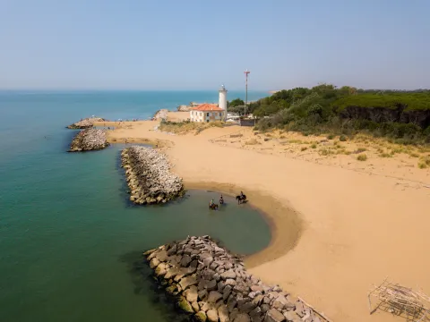Vista dall'alto di persone a cavallo sulla spiaggia del faro a Bibione