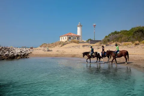 Persone a cavallo sulla spiaggia del faro a Bibione
