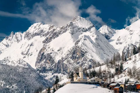 Colle Santa Lucia e chiesa con Dolomiti innevate sullo sfodno