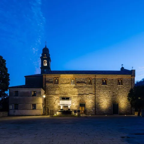 Tomba di Francesco Petrarca con chiesa di Arquà Petrarca illuminata sullo sfondo al crepuscolo