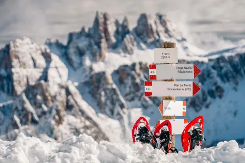 Dolomiti innevate con ciaspe e cartelli che indicano i percorsi
