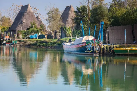 Barca tradizionale attraccata a un molo nella Laguna di CArole con i casoni sullo sfondo