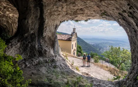 Eremo di San Donato visto dall'interno di una grotta naturale sui Colli Berici in provincia di Vicenza con due escursionisti che passeggiano