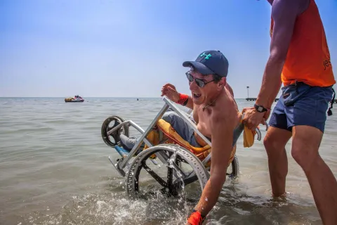 Persona con sedia a rotelle accompagnata in spiaggia a Jesolo