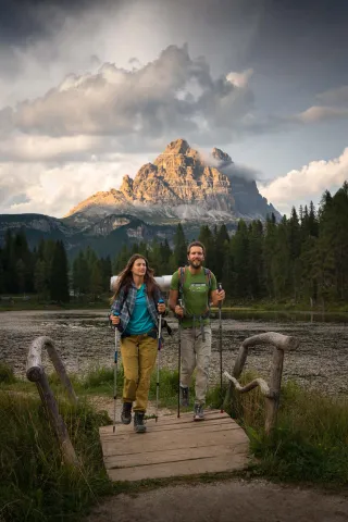 Due escursionisti davanti al Lago Antorno con le Tre Cime di Lavaredo sullo sfondo in estate