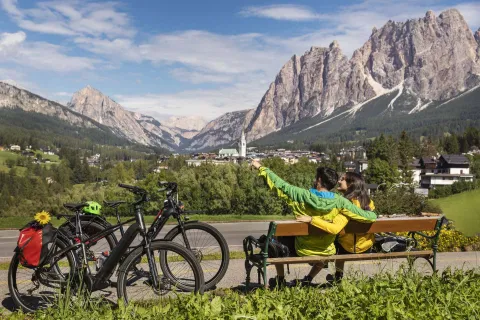 Due ciclisti si rilassano su una panchina e ammirano il panorama a Cortina