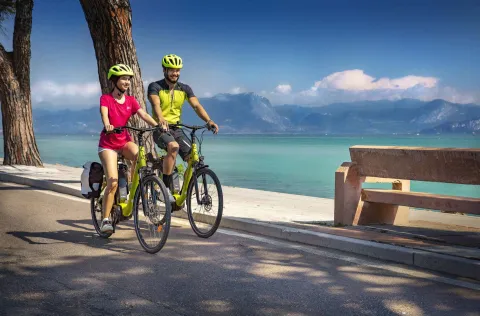 Due persone in bicicletta con il Lago di Garda sullo sfondo