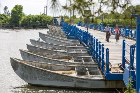 Due cicloturisti attraversano un ponte di barche a Chioggia