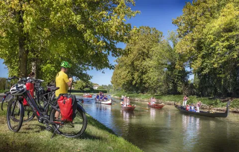 Ciclisti fermi lungo la Riviera del Brenta osservano il passaggio di varie imbarcazioni