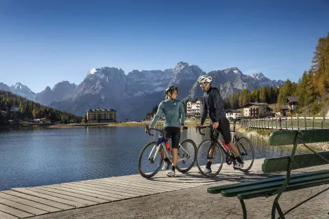 Due persone con road bike ferme sulla sponda del Lago di Misurina