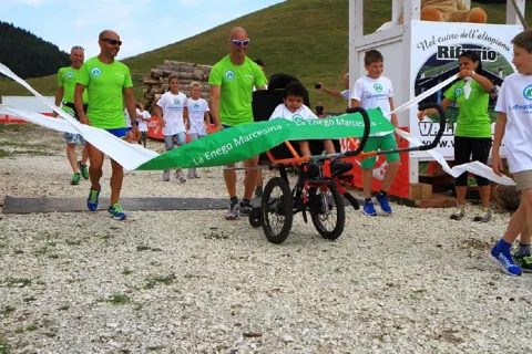 Persona in escursione su sedia a rotelle Joelette con accompagnatori a Enego