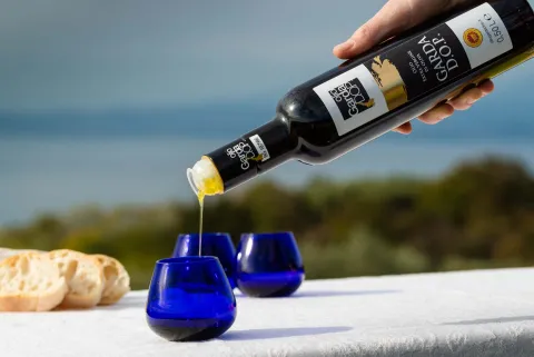 Olio del Garda versato in bicchieri per l'assaggio con sfondo del lago