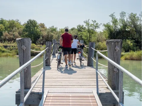 Due turisti in bici percorrono un molo dopo essere scesi dalla barca attraccata lungo il fiume