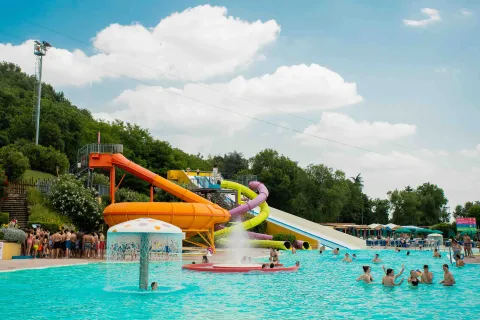 Scivoli acquatici colorati e piscina con ragazzi e ragazze che fanno il bagno in costume del Parco Acquatico Riovalli