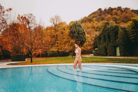 Ragazza si immerge in una piscina delle Terme Euganee durante il foliage autunnale