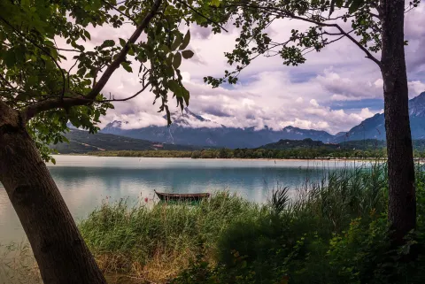 Scorcio del Lago di Santa Croce in Alpago incorniciato tra due alberi