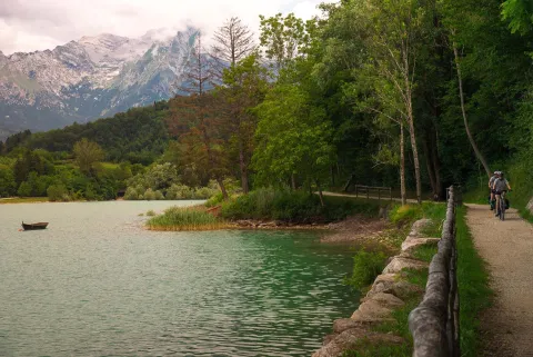Due ciclisti su sentiero che costeggia il Lago di Santa Croce in Alpago