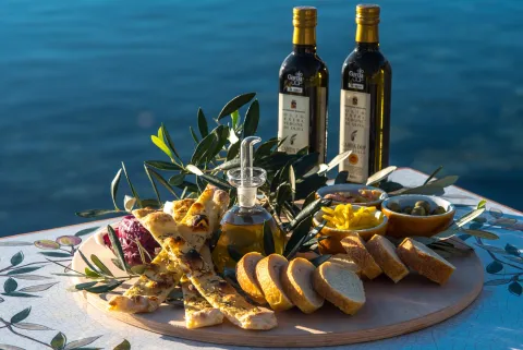 Tagliere con prodotti vari e olio del Garda con lo sfondo delle acque del lago di Garda a Bardolino