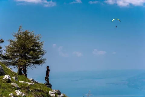 Sul Monte Baldo a Malcesine due persone e sullo sfondo un parapendio