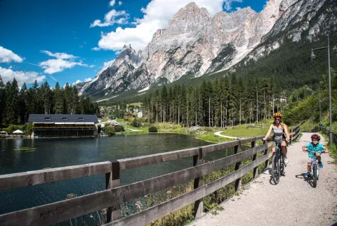 Una donna e un bambino in bici sulle rive del Lago Mosigo a San Vito di Cadore