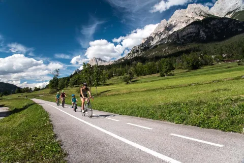 Famiglia in bici su pista ciclabile a San Vito di Cadore con Monte Antelao sullo sfondo