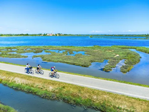 Suggestiva via con ciclisti che attraversa la laguna nord di Venezia per raggiungere il borgo storico di Lio Piccolo, una frazione di Cavallino-Treporti.