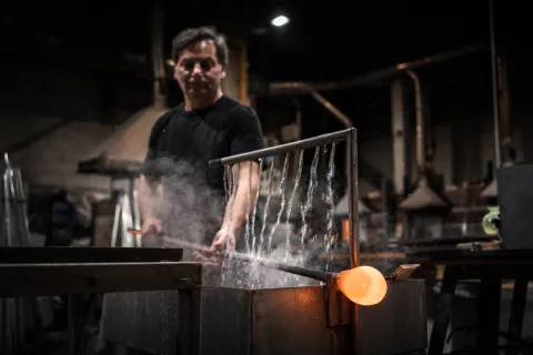 Artigiano raffredda vetro sotto l'acqua