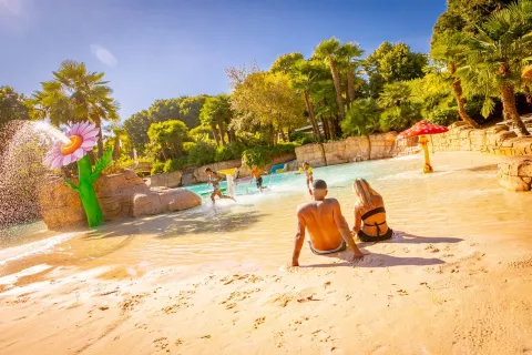 Famiglia al Parco Cavour, i genitori sono seduti in costume a bordo piscina mentre i figli giocano