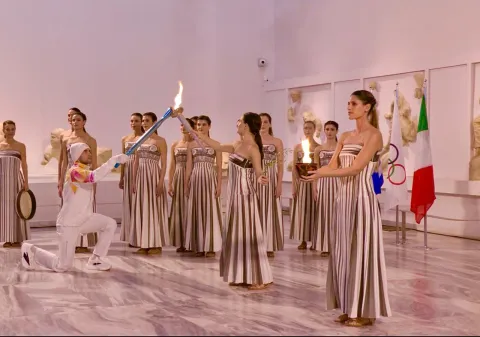 Tedoforo passa la fiamma olimpica attraverso la torcia a Olimpia per l'inizio del percorso che porterà ai Giochi Olimpici di Milano Cortina 2026
