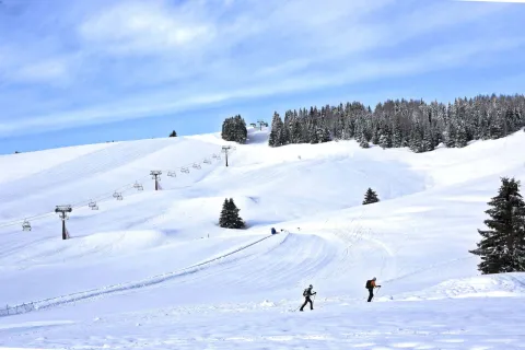 Due escursionisti con le ciaspe sull'Altopiano di Asiago Sette Comuni con seggiovia sullo sfondo