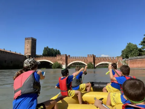 Bambini pagaiano su un kayak sull'Adige con il Ponte di Castelvecchio sullo sfondo