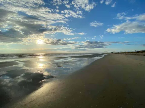 Veduta della spiaggia delle conchiglie col sole basso all'orizzonte