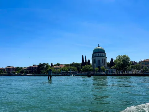 Sponda interna del Lido in cui si vedono la Laguna, le case, i palazzi e il Tempio Votivo della Pace in una giornata d'estate con il cielo limpido
