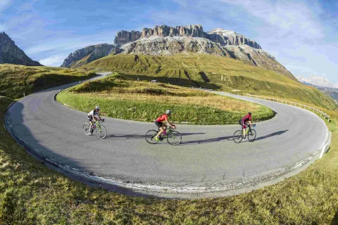 Tre ciclisti effettuano un tornante a Passo Pordoi sul percorso Sellaronda