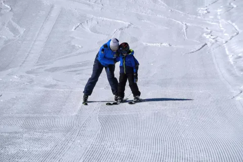 Istruttore insegna a un bambino a sciare sull'Altopiano di Asiago Sette Comuni