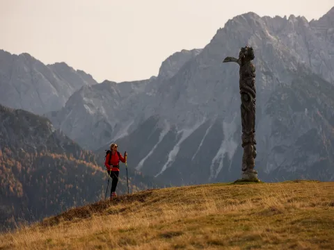 Escursionista davanti al totem in legno del Monte Zovo lungo il Cammino degli Alti Pascoli