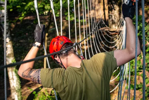 Ragazzo cammina su un ponte di corde legato dai moschettoni al Veja Adventure Park